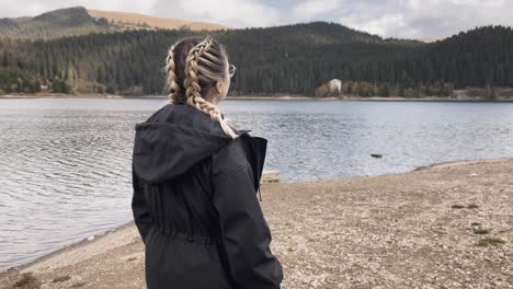 a woman walking on the shoreline of bolboci lake during cloudy day in romania