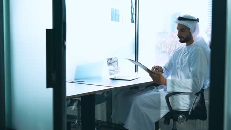 handsome man with traditional clothes working in an office of dubai