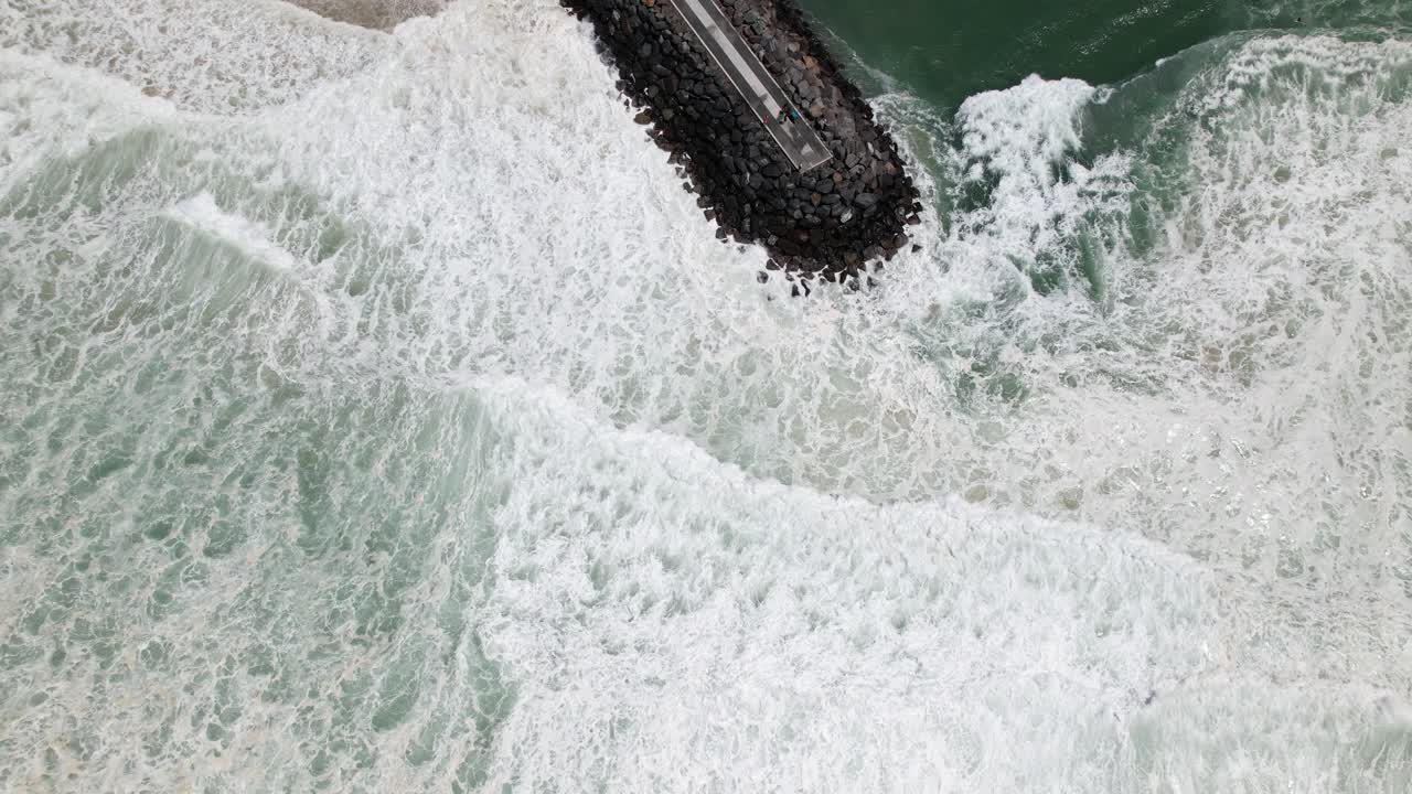 White Waves Splashing On Tallebudgera Seawall During Cyclone Alfred In Queensland, Australia. aerial topdown shot