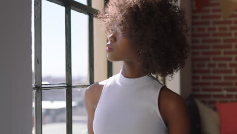 stylish black woman using smartphone at home browsing messages enjoying relaxed lifestyle looking out window african american female texting on mobile phone