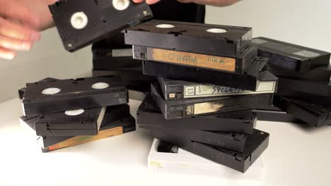 un hombre está arreglando pilas de cintas vhs