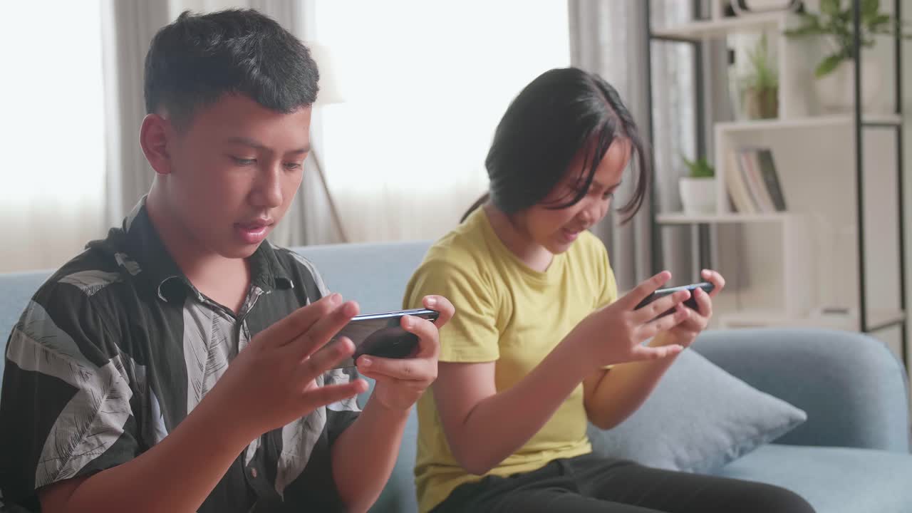 Children Playing Mobile Games on Sofa