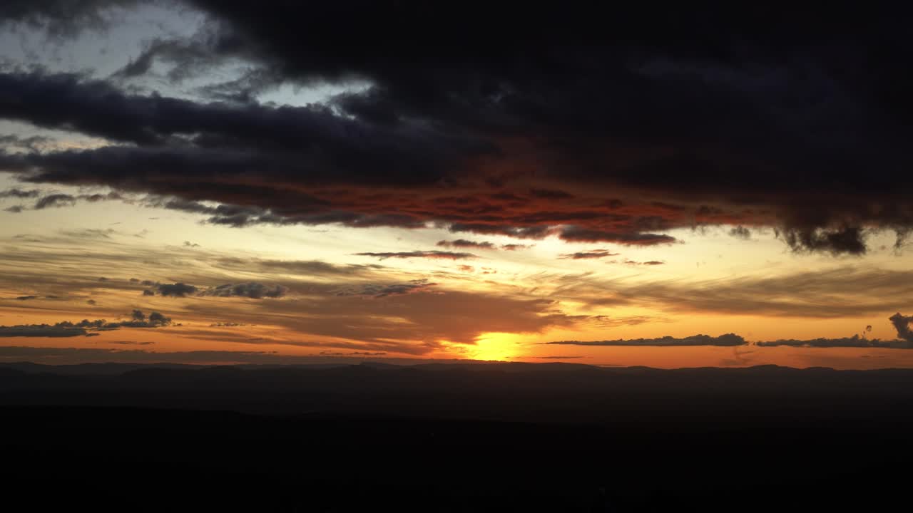 Eine nach unten schwenkende Weitwinkelaufnahme enthüllt einen wunderschönen, lebhaften goldenen Sonnenuntergang von der Spitze des berühmten Morro Pai Inacio im Chapada Diamantina Nationalpark in Bahia, Nordostbrasilien, an einem Sommerabend.
