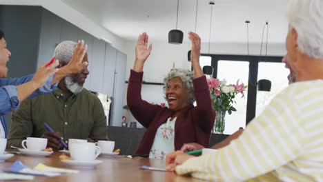 happy senior diverse people drinking tea and playing bingo at retirement home