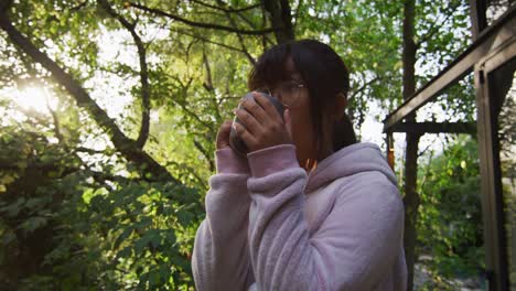 Chica-Asiática-Bebiendo-Té-En-El-Jardín-Y-Sonriendo.