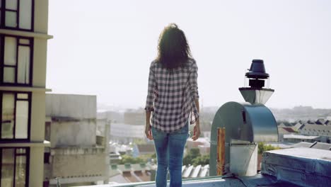 Fashionable-young-woman-on-urban-rooftop-admiring-the-view