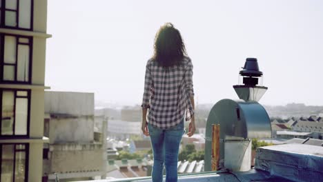 mujer joven de moda en el techo urbano admirando la vista