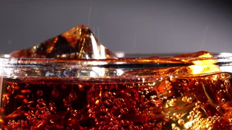 Cola-with-Ice-and-bubbles-in-glass-slow-motion.