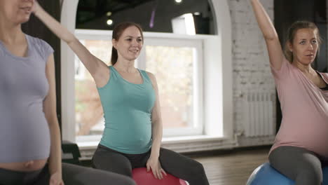 camera focusing on a pregnant woman in yoga class surrounded by classmates