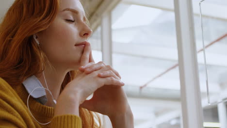 female graphic designer listening music on headphones in office 4k