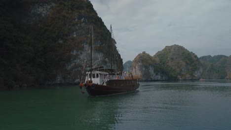 Barco-Pesquero-Navegando-Por-Acantilados-De-Piedra-Caliza-En-La-Bahía-De-Lan-Ha,-Vietnam