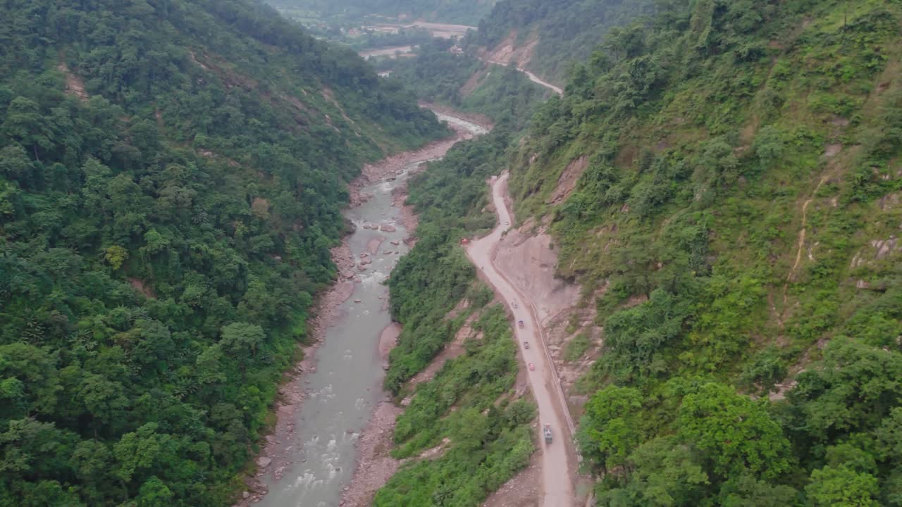 Beautiful aerial view of a river flowing through a valley between two mountains, surrounded by lush green hills, forests, and natural landscapes — a peaceful and breathtaking mountain scene