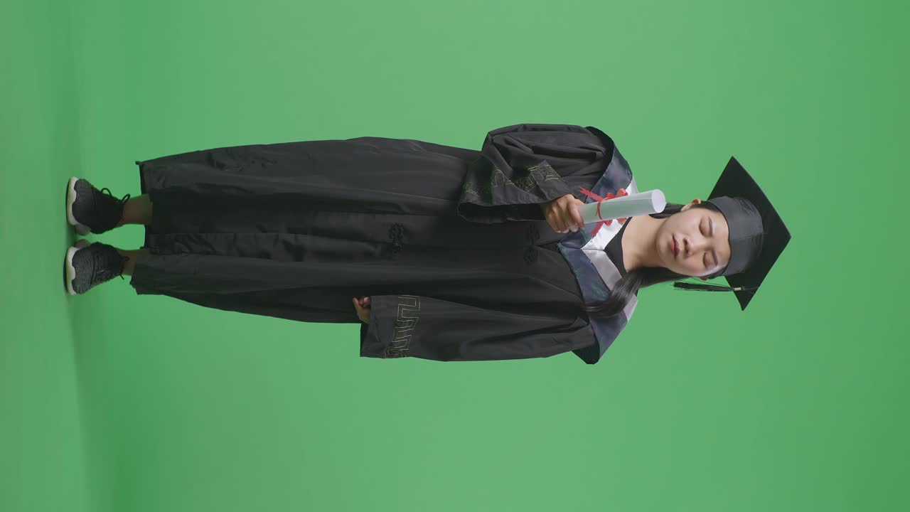 Donna in toga di laurea che tiene un diploma su schermo verde