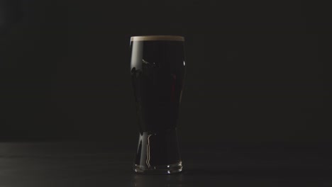 pinta de cerveza negra irlandesa en vidrio contra el fondo negro del estudio para celebrar el día de san patricio
