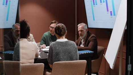professionals engaging in a business meeting with charts on display