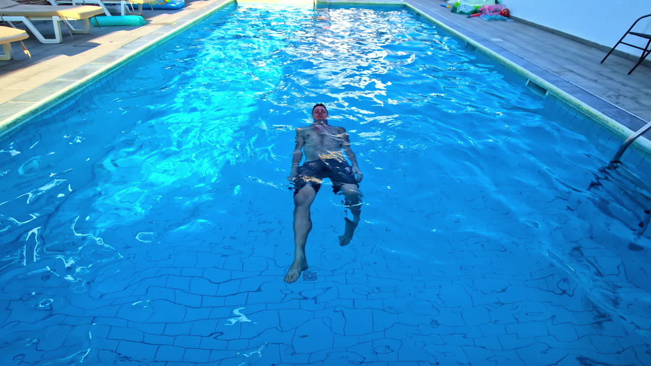 Uomo in piscina in un hotel o resort - acqua blu brillante.