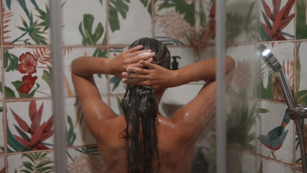 Donna che si lava i capelli sotto la doccia
