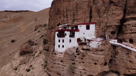 gompa build on cliff face in mulbekh, the most western buddhist settlement in ladakh. drone aerial orbit close up