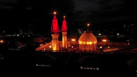 Una-Foto-Nocturna-Tomada-Por-Un-Dron-De-Visitantes-Y-Peregrinos-Chiítas-En-La-Mezquita-Y-El-Santuario-Del-Imam-Hussein-Y-Abbas-En-Karbala,-Irak.