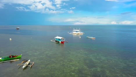 Canoes-and-bangka-boats-drifting-in-shallows-in-Philippines,-drone-approaching-shot