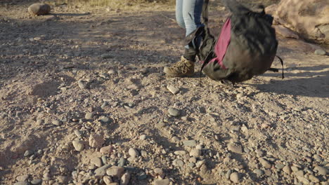 women hiker drops pack in dirt on desert hike to make camp