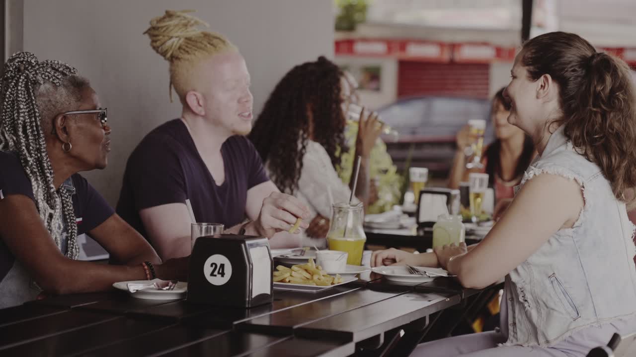 Diverse Group of Friends Enjoying a Meal and Conversation at an Outdoor Cafe