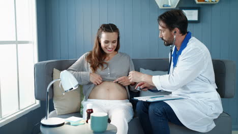 closeup doctor checking pregnant belly with stethoscope in office.