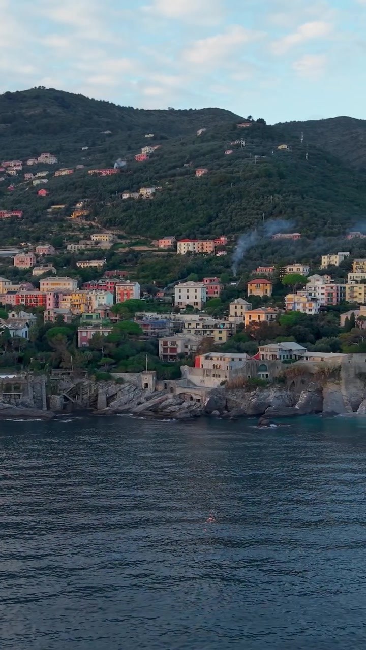 Panoramica aerea verticale di una città costiera e dell'architettura collinare sulla Riviera Ligure.