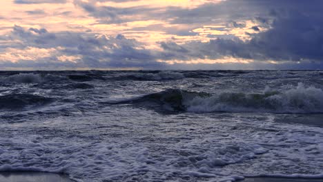 waves at sea during a thunderstorm at sunset