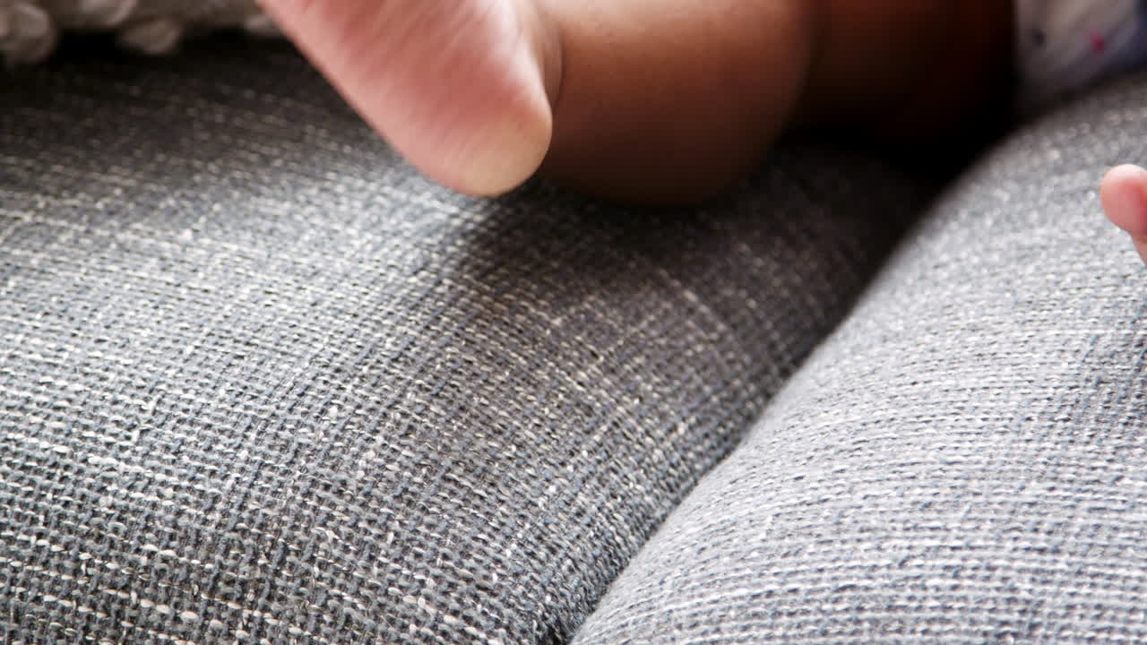 집에서 소파에 앉아 발가락으로 놀고 있는 아기 소녀의 근접 사진