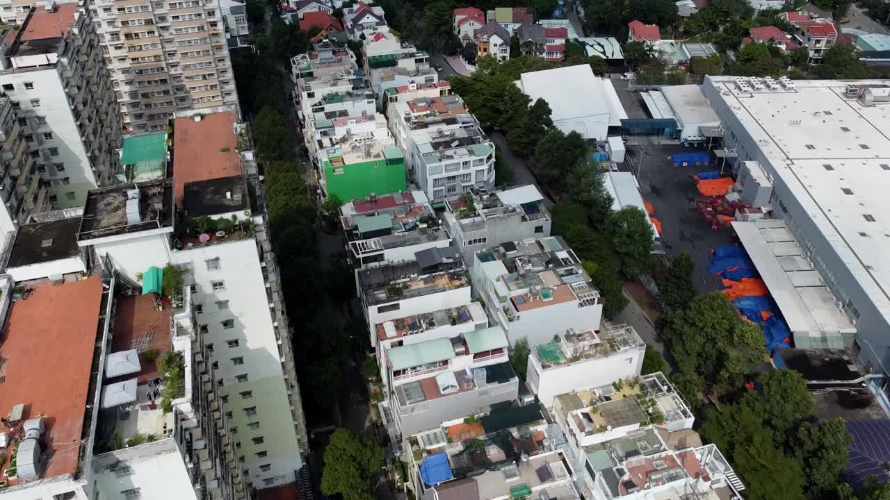 Bird's eye view above apartment buildings and homes lined with trees, vietnam
