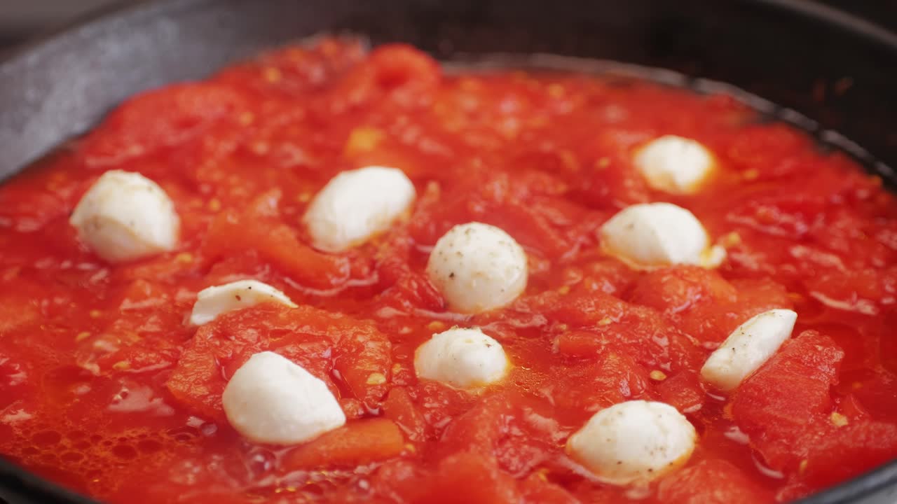 Cooking fresh peeled canned tomato Juice sauce with mozzarella cheese in pan, peeled tomatoes boiling in their own juice, making tomatoes pasta sauce .Top view close up, Italian traditional cuisine food.