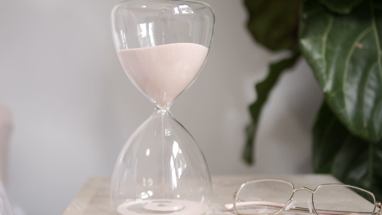 Hourglass Sands Fall On Bedside Table In Sunlit Room, SLOW MOTION