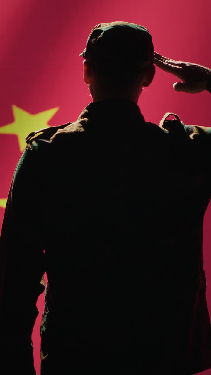Vídeo vertical. Soldado fazendo gesto de continência em direção à bandeira chinesa.