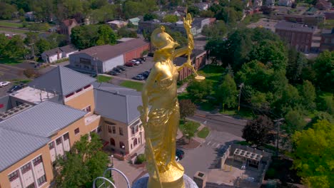 drone revolves around the gold justice statue on top of the beautiful courthouse in canandaigua, new york near canandaigua lake