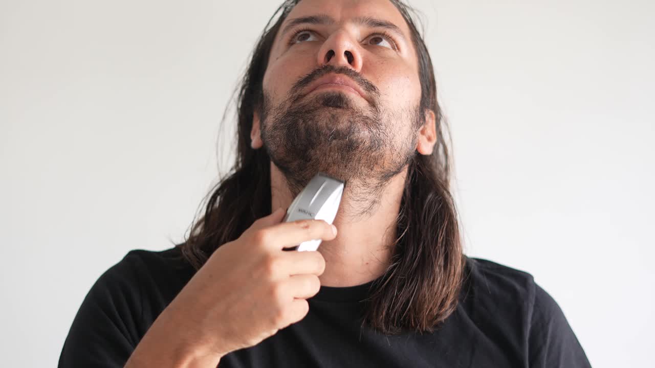 Uomo latino che rifinisce barba e baffi con rasoio elettrico, Balsamo da barba