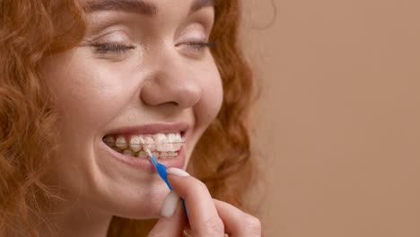mujer limpiando sus aparatos ortopédicos con un cepillo interdental