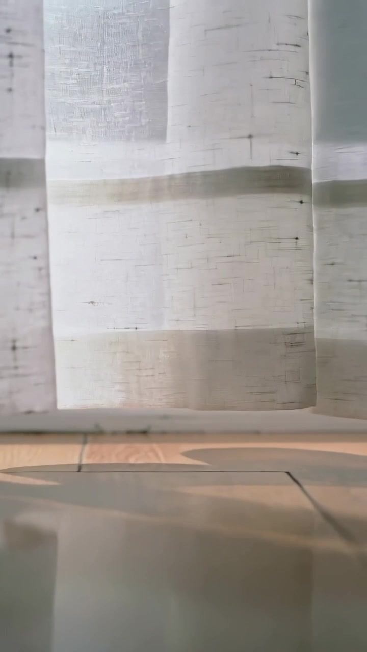 Video verticale: Luce solare che filtra e spinge una tenda velata che ondeggia alla finestra, creando ombre sul pavimento.