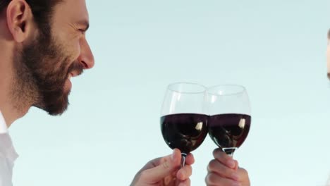 una pareja romántica sonriente brindando copas de vino