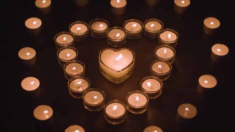 romantic white candles in the shape of a heart on black background