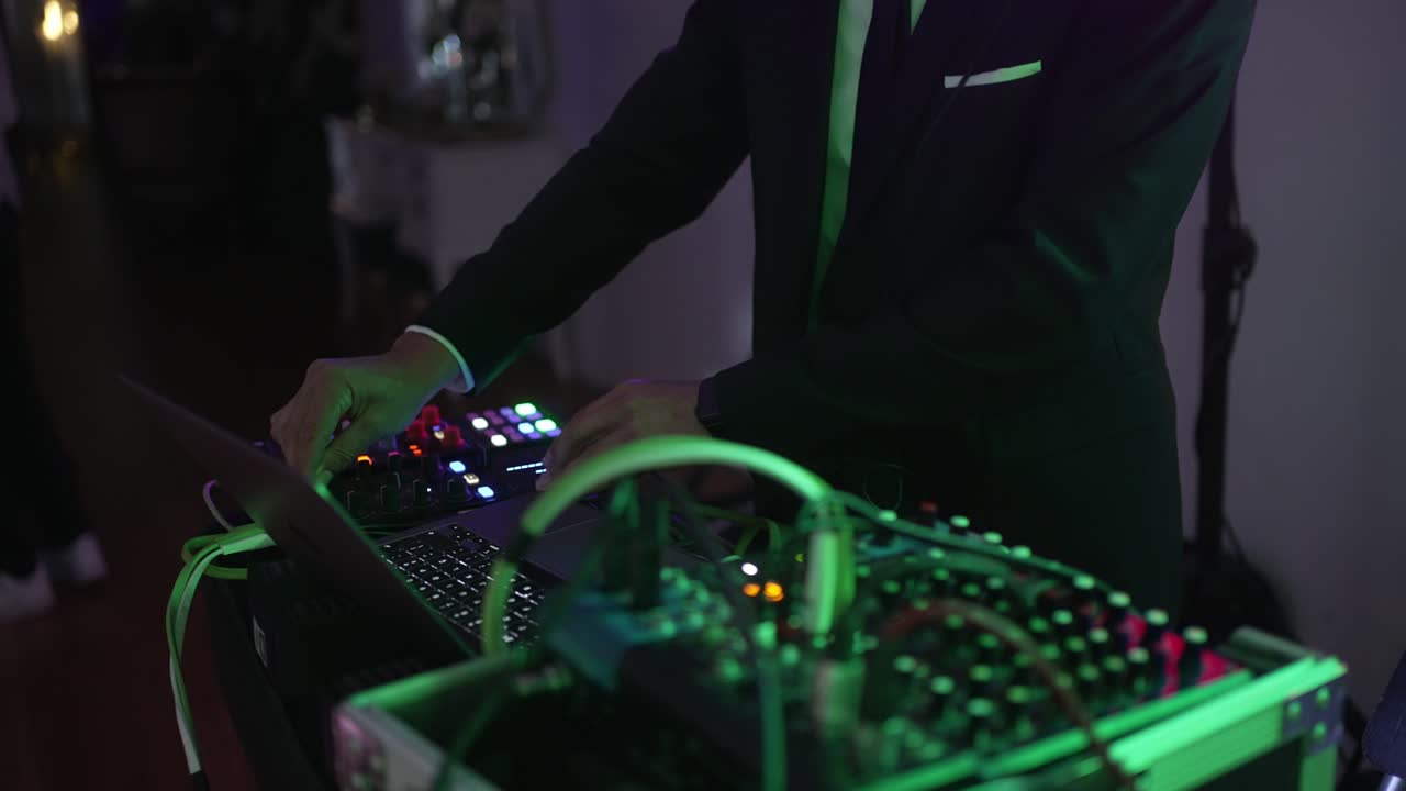 DJ operating a sound mixer with illuminated controls, setting the ambiance for an evenr