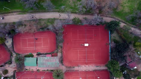 static aerial overhead view of red clay tennis courts with people playing a match, o'higgins park, santiago, chile