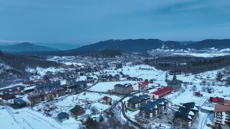 An-aerial-view-of-a-snow-covered-mountain-town,-with-buildings-and-streets-blanketed-in-fresh-snow