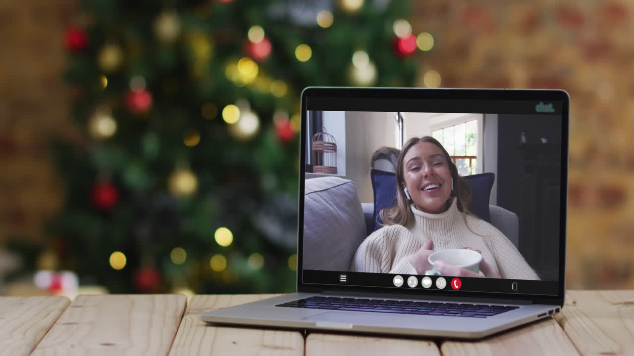mujer caucásica feliz en videollamada en computadora portátil, con decoraciones de navidad y árbol