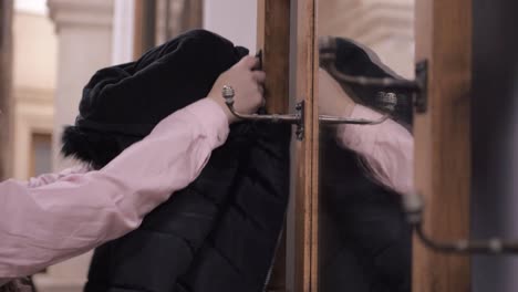 woman hanging coat on vintage ornate coat hanger hooks