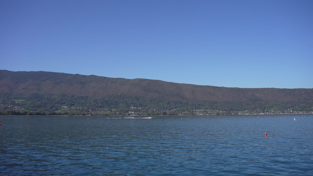 водный лыжник тянется на моторной лодке на озере аннеси во французских альпах, панорама справа следовать выстрелу