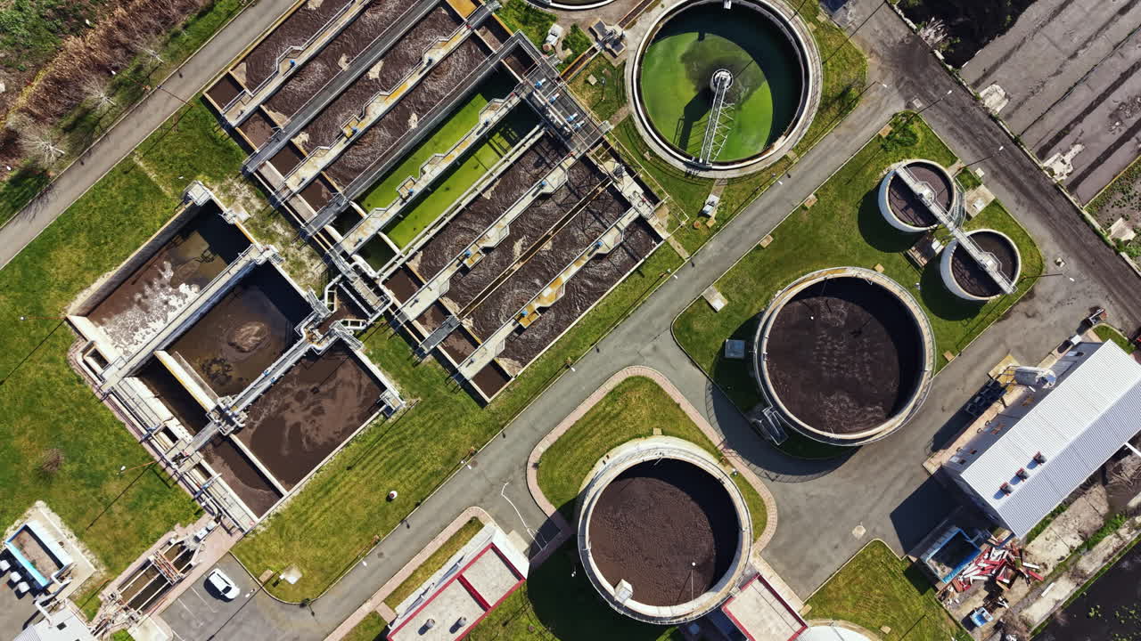 Water treatment facility is shown from above, highlighting various tanks and structures on a clear day in an industrial area