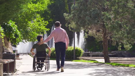 un adolescente discapacitado está conduciendo su silla de ruedas y caminando con su amigo.