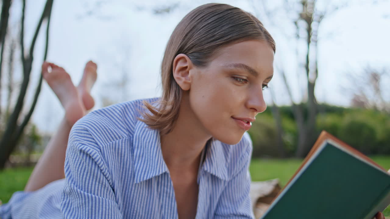 Relaxed student reading literature lying green park grass closeup. Smiling woman