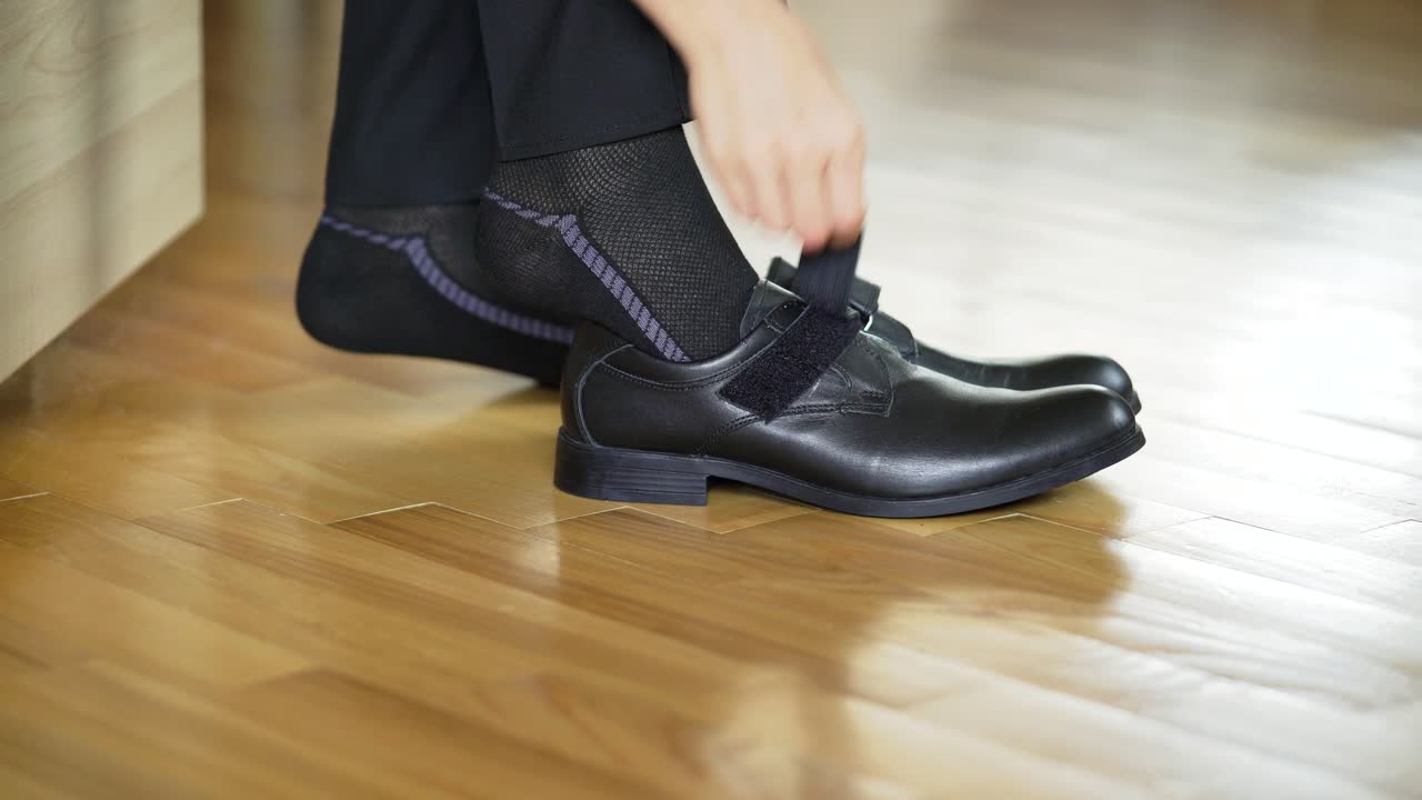 Boy put on ones shoes. Close up view of boys legs put on shoes